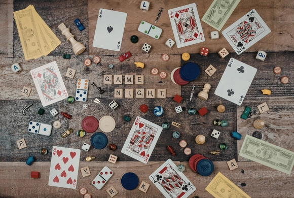 Photo of a table covered in a variety of game pieces from different tabletop and card games. 