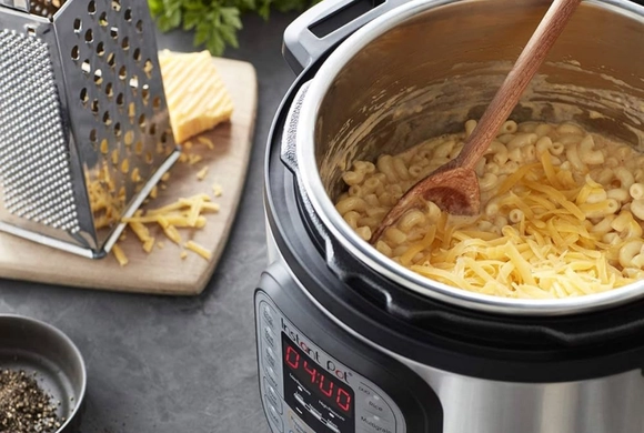 Photograph of an open Instant Pot with other kitchen gadgets in the background.